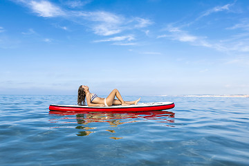 Image showing Woman relaxing over a paddle surfboard