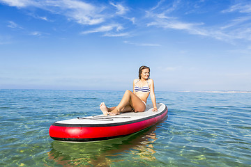 Image showing Woman sitting over a paddle surfboard