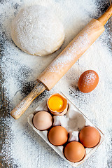 Image showing Dough, rolling pin and a tray of eggs.