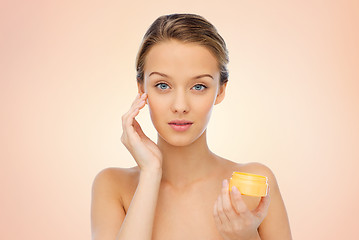 Image showing young woman applying cream to her face