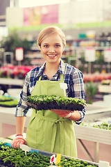 Image showing happy woman holding seedling in greenhouse