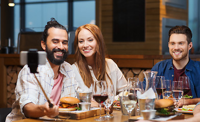 Image showing friends taking selfie by smartphone at restaurant