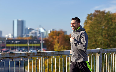 Image showing happy young man running over city bridge