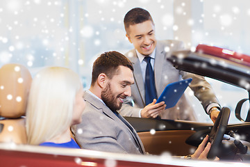 Image showing happy couple with car dealer in auto show or salon