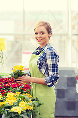 Image showing happy woman holding flowers in greenhouse