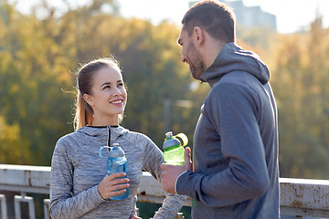 Image showing smiling couple with bottles of water outdoors