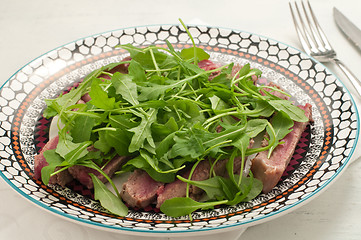 Image showing Sliced beef cooked in the oven with salt, pepper and rocket