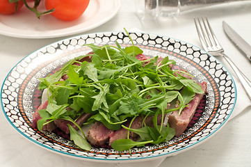 Image showing Sliced beef cooked in the oven with salt, pepper and rocket