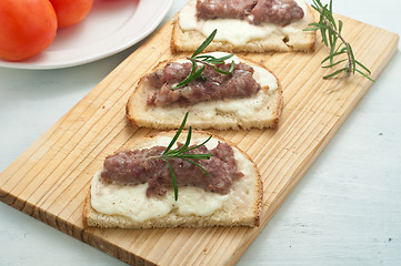 Image showing Crispy bruschetta topped with sausage and fresh rosemary