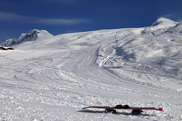 Image showing Snowboard in snow on ski slope at sun windy evening