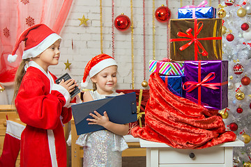 Image showing Santa Claus and assistant recount gifts in a bag