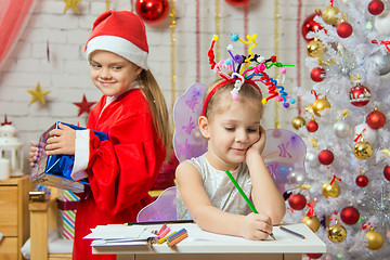 Image showing Girl sits at a table with fireworks on the head, Santa Claus brings her Christmas gift