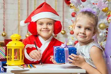 Image showing Santa Claus and fairy helper prepared greeting cards and presents