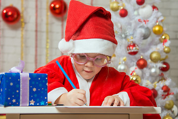 Image showing Girl enthusiastically prepares a gift card for Christmas