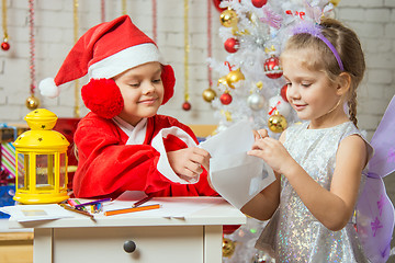 Image showing Girl dressed as Santa Claus puts a congratulatory letter in the envelope that holds the girl fairy