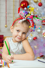 Image showing Girl with a toy fireworks on the head draws pencil on a sheet