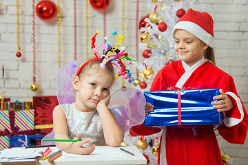 Image showing Girl sits at a table with fireworks on the head, Santa Claus brings her a gift