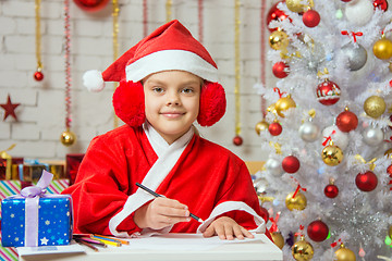 Image showing Girl dressed as Santa Claus prepares New Years greetings