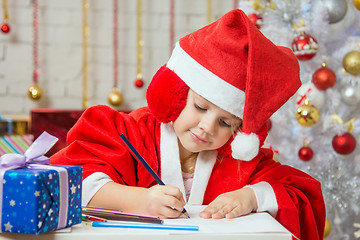 Image showing Girl with enthusiasm writes congratulations Christmas card