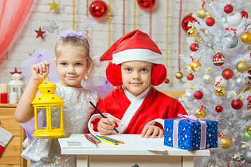 Image showing  Father Frost wrote a congratulatory letter to the assistant fairy standing next to a candlestick in his hand