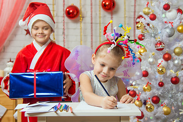 Image showing Girl sits at a table with fireworks on the head, Santa Claus is preparing to surprise her