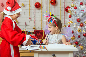 Image showing Girl sits at a table with fireworks on the head, Santa Claus gave her a gift