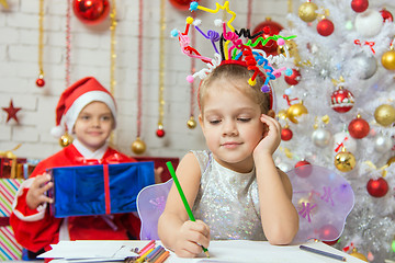 Image showing She writes a letter to Santa Claus, who is sitting with a gift behind her