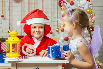 Image showing Santa Claus and fairy fun to look at each other\'s assistant preparing greeting cards and gifts