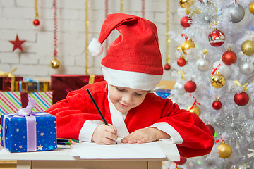 Image showing Girl dressed as Santa Claus writing a list of desired gifts for Christmas