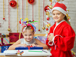 Image showing Girl sits at a table with fireworks on the head with a gift that is presented to Father Christmas