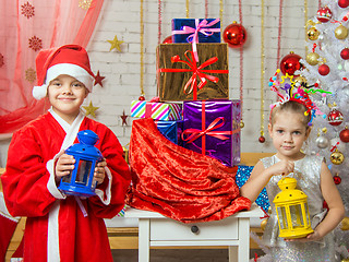 Image showing Two girls in Christmas costumes are with candlesticks from the bag with Christmas gifts