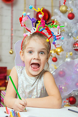 Image showing Girl with a toy fireworks on the head draws a congratulatory New Years card