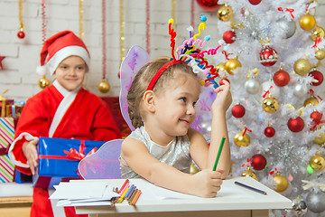 Image showing The girl picked up a toy fireworks on the head, Santa Claus sitting behind her