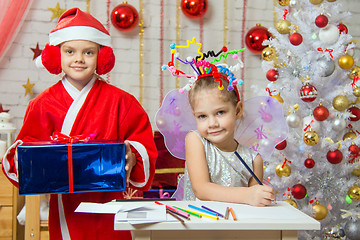 Image showing Girl sits at a table with fireworks on the head, Santa Claus is a little behind with a gift