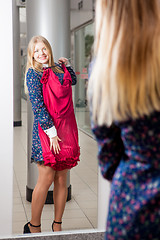 Image showing Woman trying red dress shopping for clothing. 