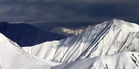 Image showing Panoramic view on snowy sunlit mountains and overcast sky