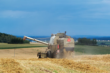 Image showing old combine on field harvesting gold wheat