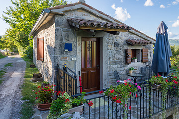 Image showing small stone house with a metal fence