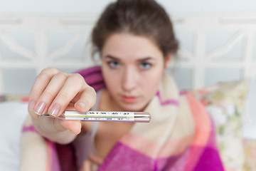Image showing Young sick woman in blanket with thermometer 