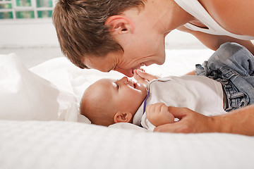 Image showing young father with his nine months old son on the bed at home