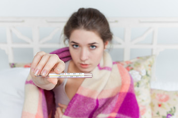 Image showing Young sick woman in blanket with thermometer 