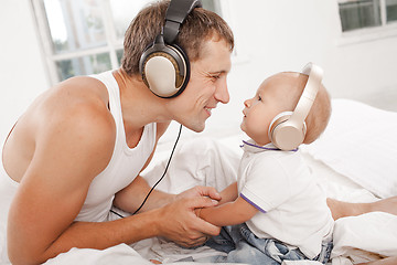 Image showing young father with his nine months old som on the bed at home