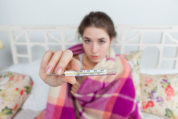 Image showing Young sick woman in blanket with thermometer 