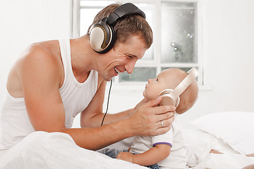 Image showing young father with his nine months old som on the bed at home