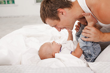 Image showing young father with his nine months old son on the bed at home