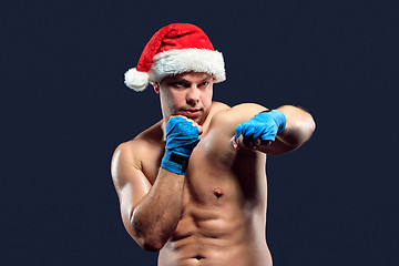 Image showing Christmas fitness boxer wearing santa hat boxing on black 