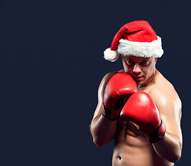 Image showing Christmas fitness boxer wearing santa hat boxing on black background