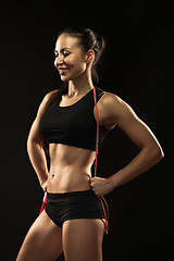 Image showing Muscular young woman athlete with a skipping rope on black 