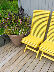 Image showing House exterior decorated with yellow chairs and flowers