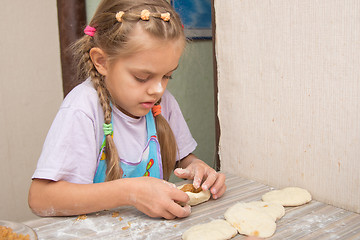 Image showing Six year old girl concentrating sculpts cakes with cabbage